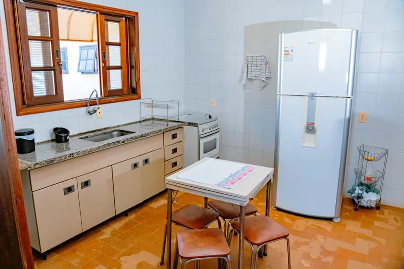 Cozinha com geladeira, fogão e mesa