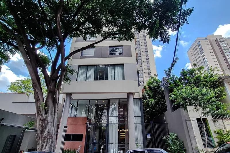 A fachada, na rua arborizada