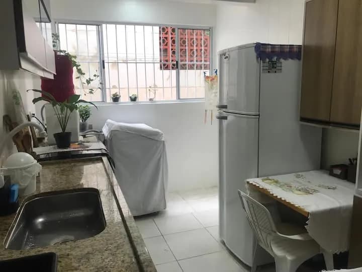 cozinha com geladeira, freezer e mesa de refeições