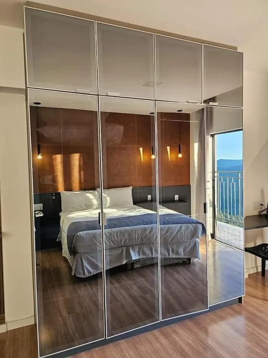 Armário espelhado reflete a cama e a serra