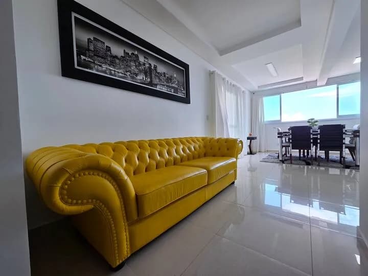 sofá Chesterfield amarelo, mesa de jantar ao fundo