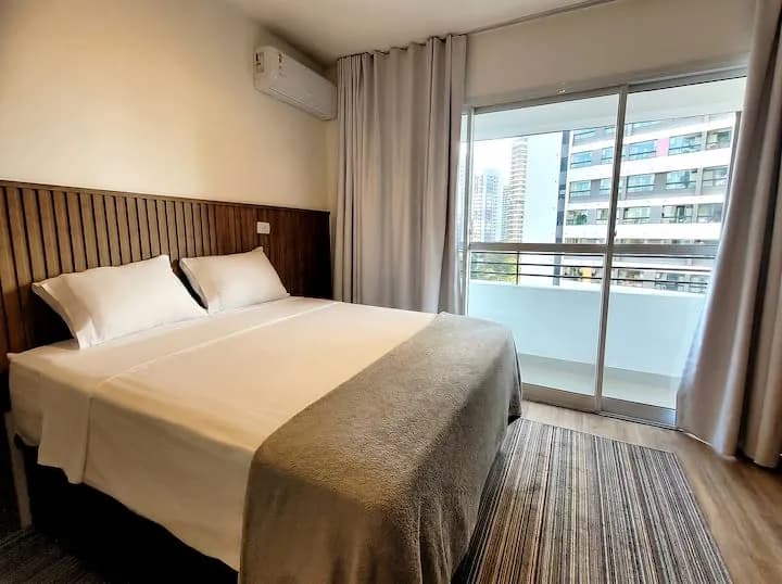 cama queen com painel de madeira e varanda